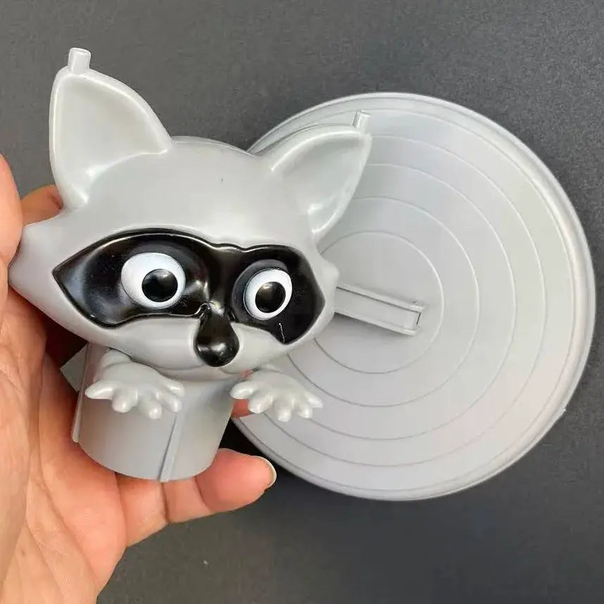 Toilet paper holder with a cute gray raccoon figure mounted on a round wall base