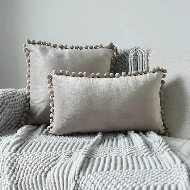 Velvet cushion covers by Simples Market, set of 2 cream cushions with tassel fringe on a gray knit throw.