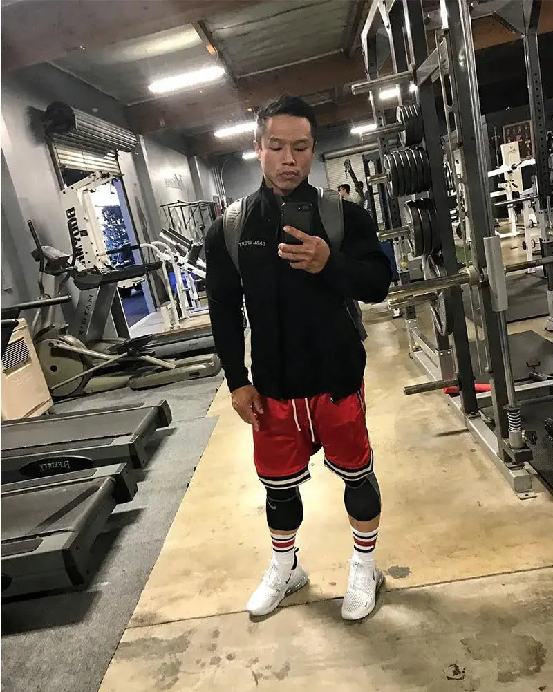 Men's basketball shorts by Simples Market, red mesh quick-dry gym shorts shown in a gym.