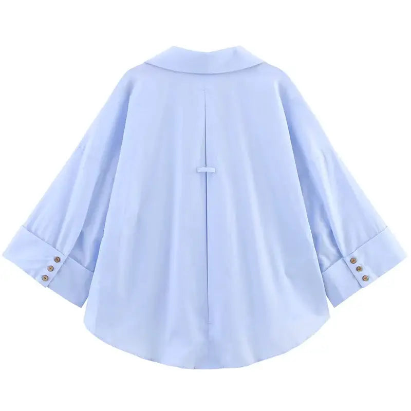 Women's oversized light-blue shirt with long sleeves, back view, curved hem.