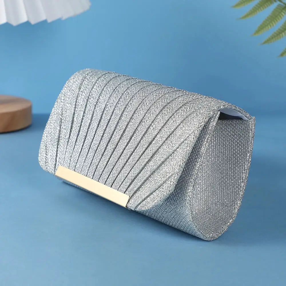 Silver sequined clutch bag with diagonal ribbed pattern and gold-tone bar for evening events