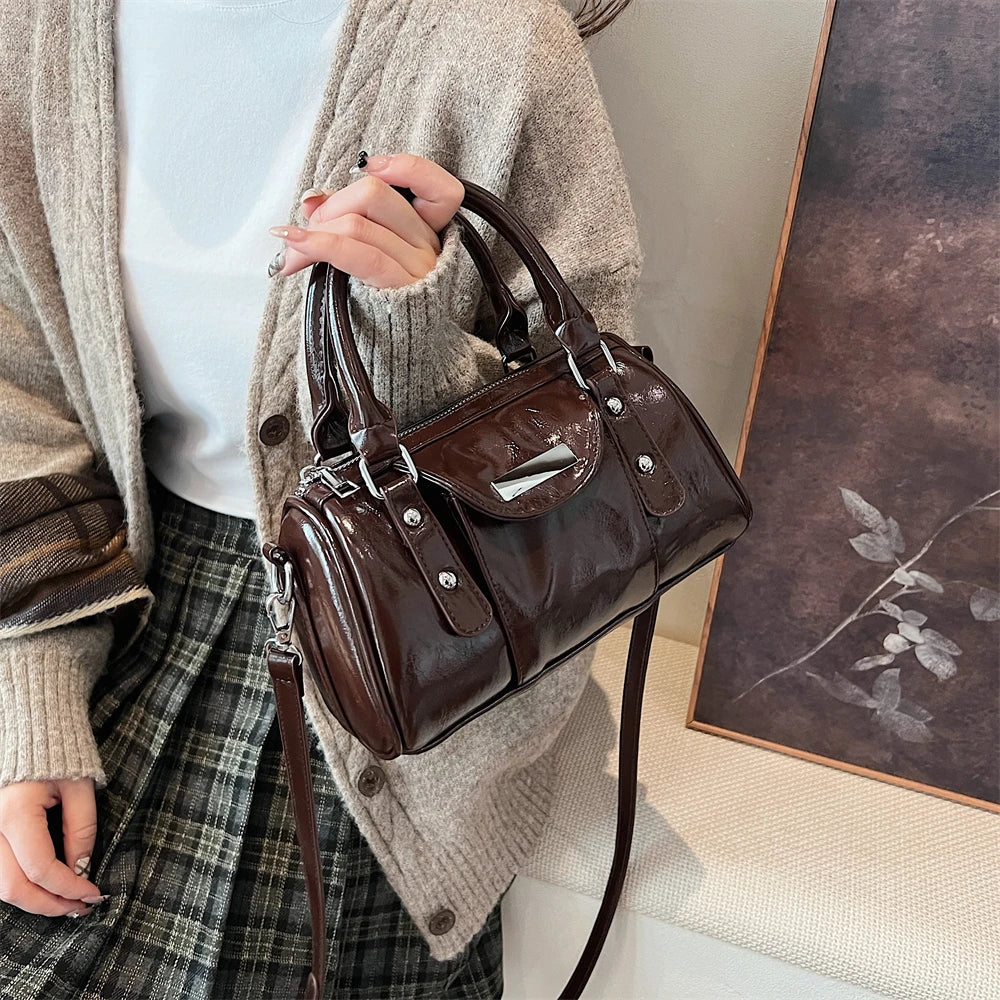 Burgundy mini top-handle handbag in glossy PU leather with crossbody strap and silver hardware