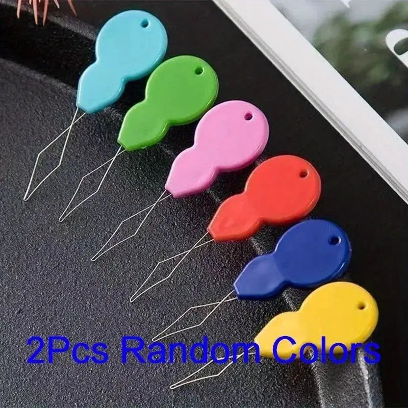 Six colorful plastic needle threaders for hand sewing, displayed in turquoise, green, pink, orange, blue, and yellow.