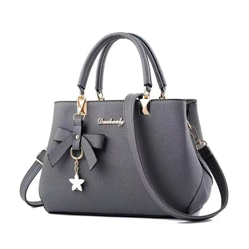 Grey textured bow handbag with double top handles and removable shoulder strap, gold hardware by Simples Market.