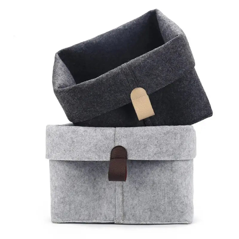 Two gray felt storage baskets with leather straps, stacked for dorm or home organization