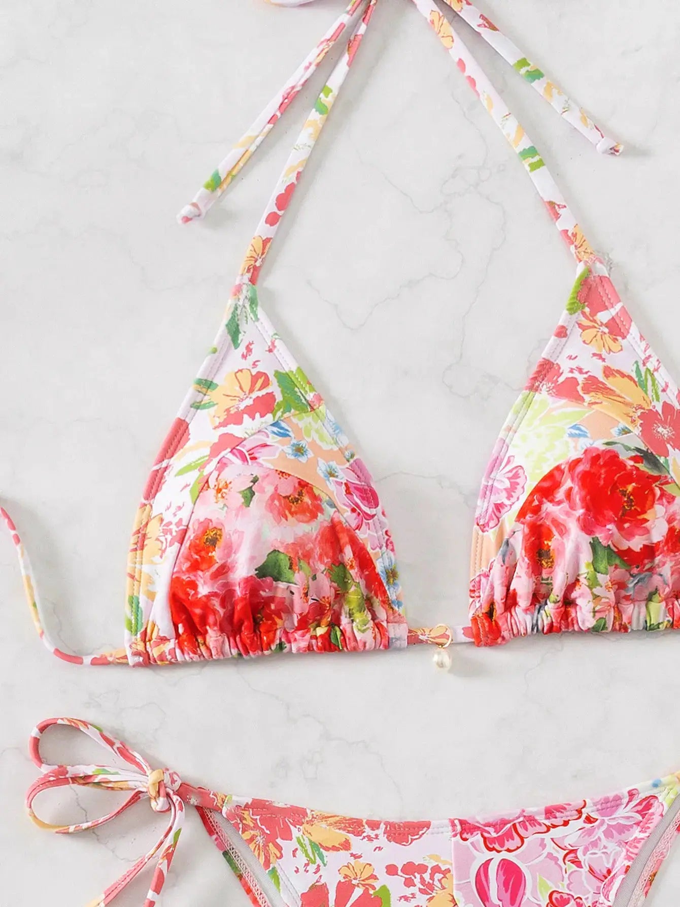 Floral print triangle bikini set with white base; pink, red and yellow flowers, string-tie top and bottoms