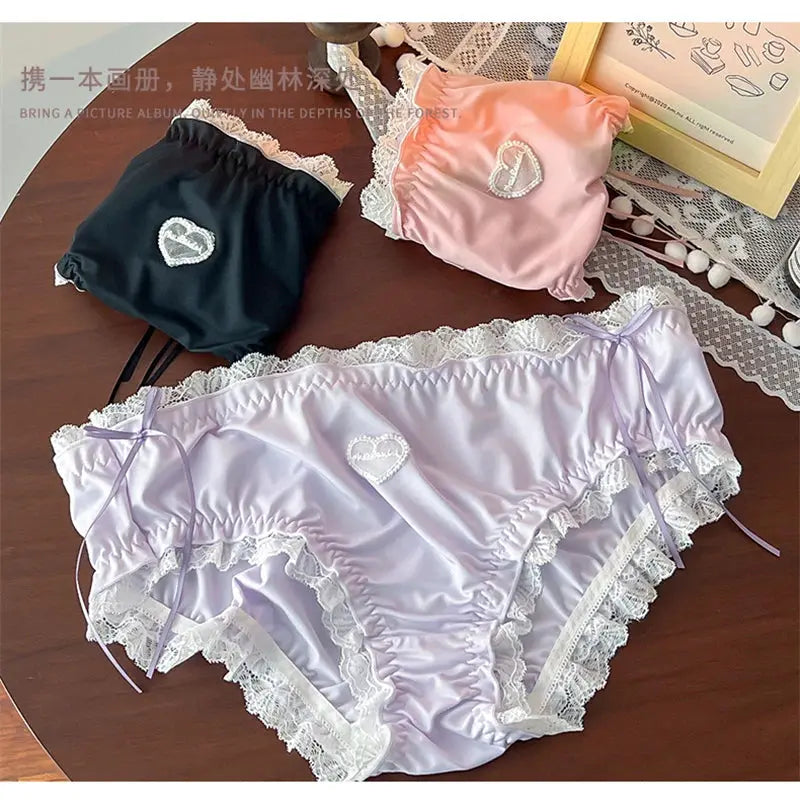 Three satin lace-trim panties in lilac, black, and pink with heart embroidery; plus-size lingerie.