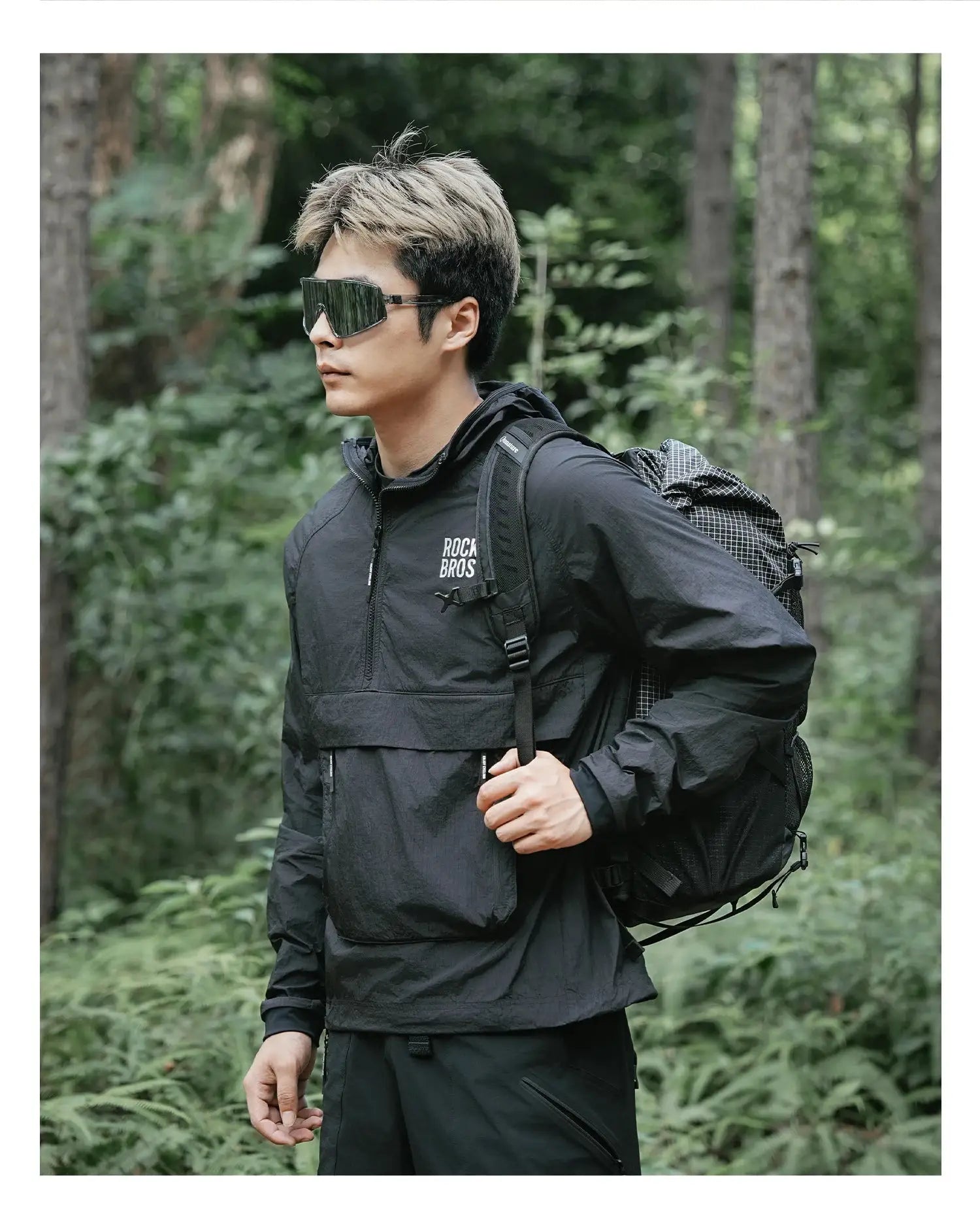 ROCKBROS black cycling waterproof jacket with detachable pocket, worn with a backpack in the forest