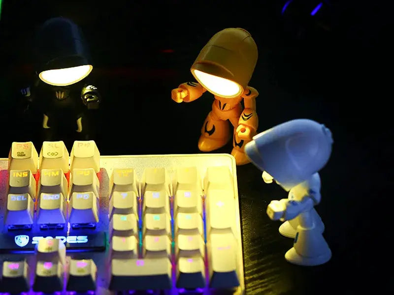Three mini LED night light cartoon hero police desk lamps (blue, orange, black) around a backlit keyboard.