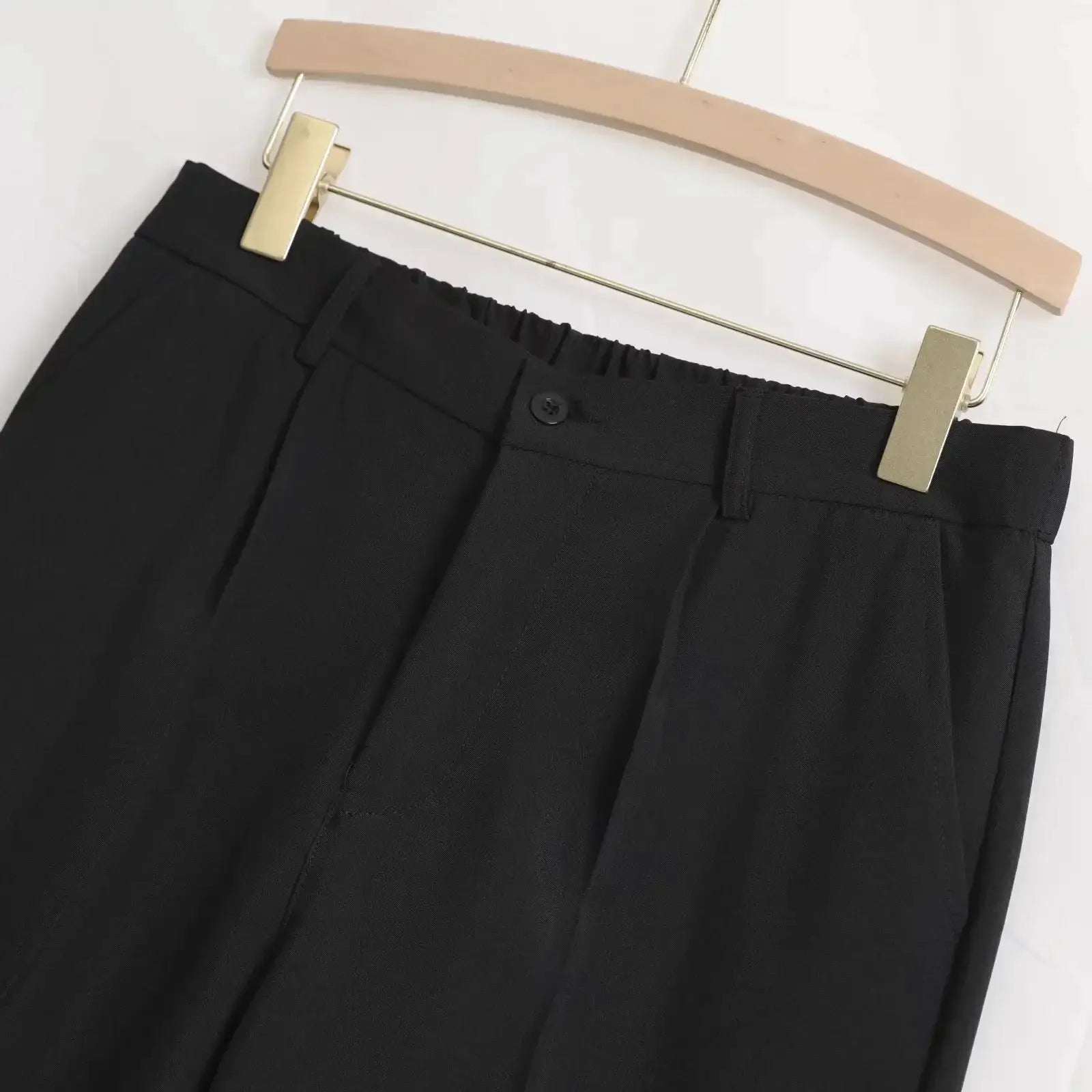 Men's black straight baggy casual pants on a hanger with elastic back waist and button closure.