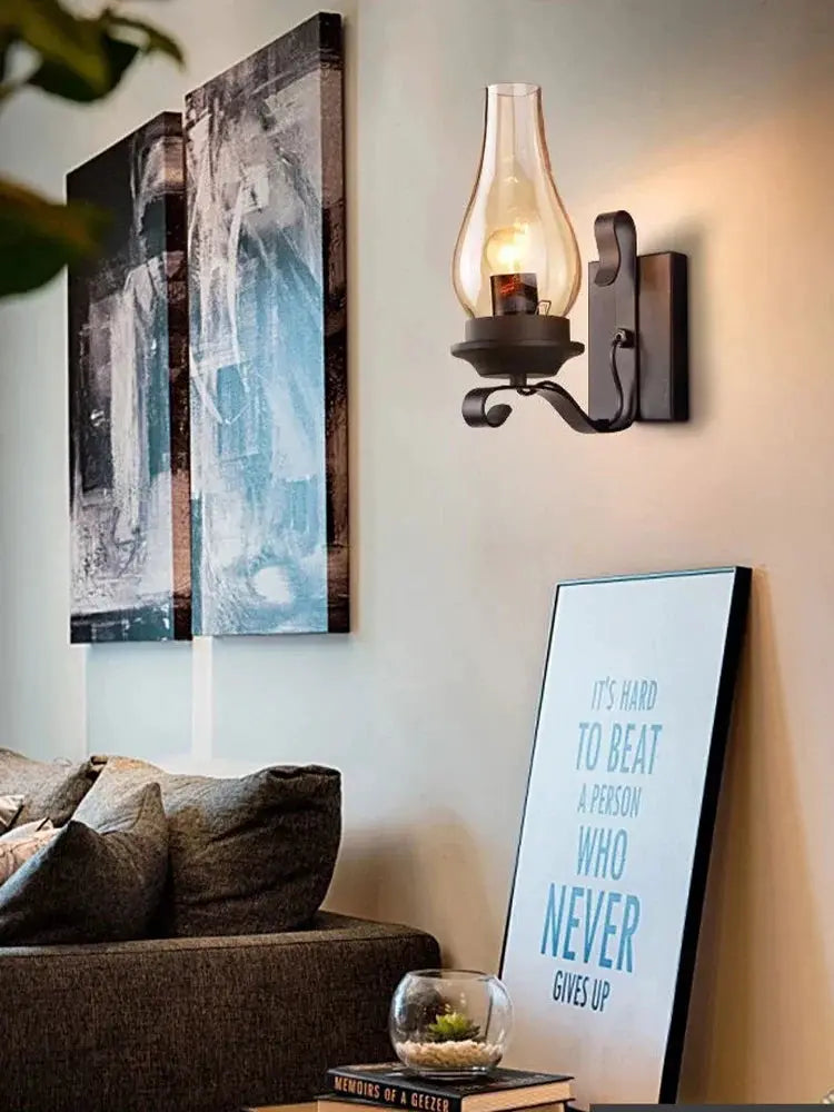 Wall sconce lamp in black wrought iron with a clear teardrop glass shade.