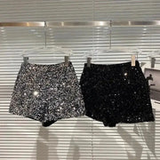 Two sequined shorts, silver and black, hanging on display; shiny clubwear hot pants for women