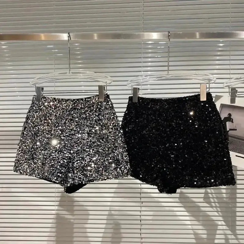 Two sequined shorts, silver and black, hanging on display; shiny clubwear hot pants for women