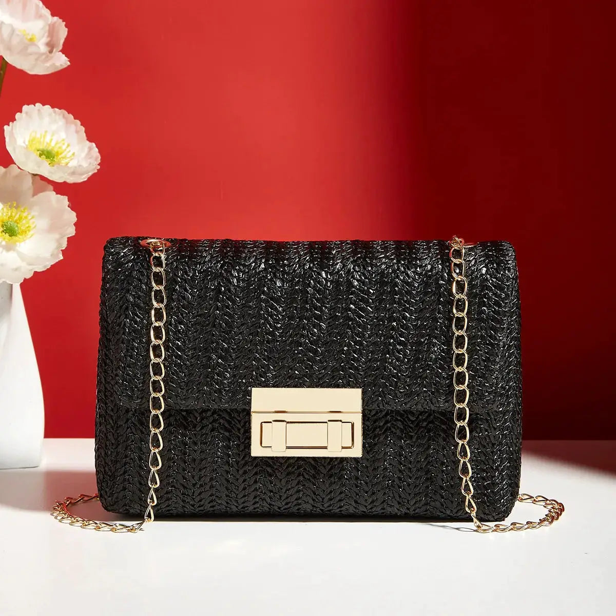 Crossbody bag for women, black textured finish with gold chain strap and gold-tone rectangular turn-lock.