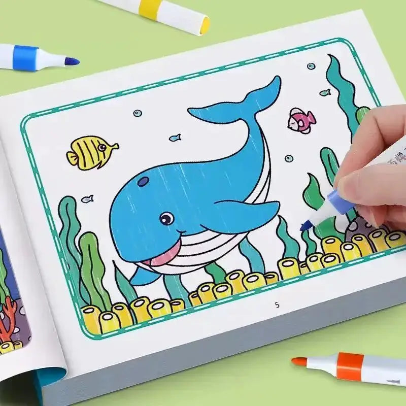 Kids coloring book page featuring a blue whale with seaweed and coral, with markers nearby.