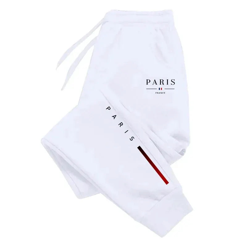 White men's Paris printed sweatpants with black PARIS lettering, red leg stripe, drawstring waist, and cuffed ankles.