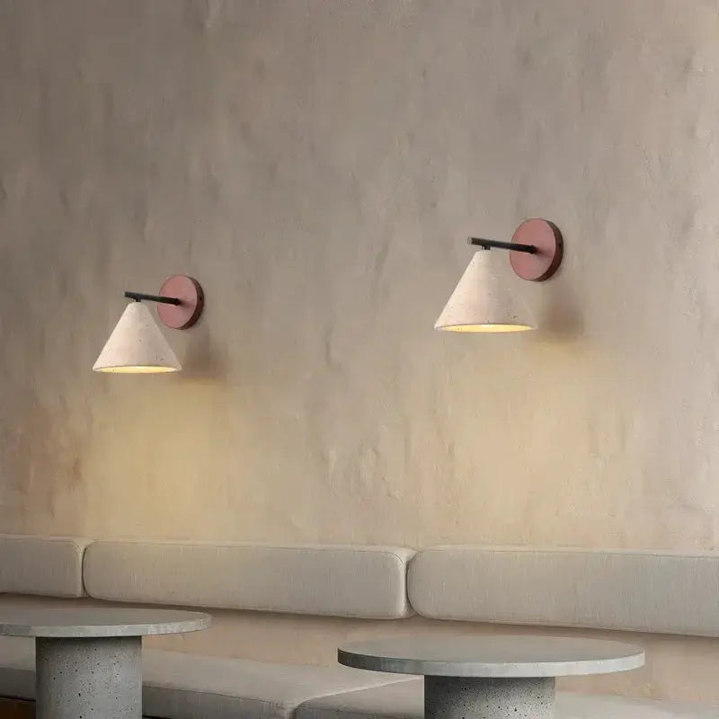 Travertine wall sconces, pair with cone-shaped shades, warm yellow glow on beige textured wall