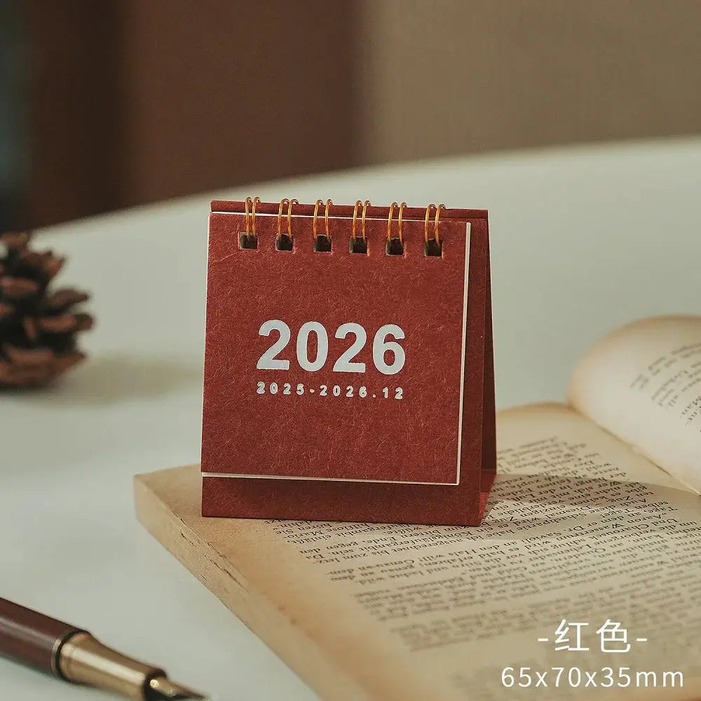 Red mini desk calendar 2026 with gold coil binding, compact 65x70x35mm.