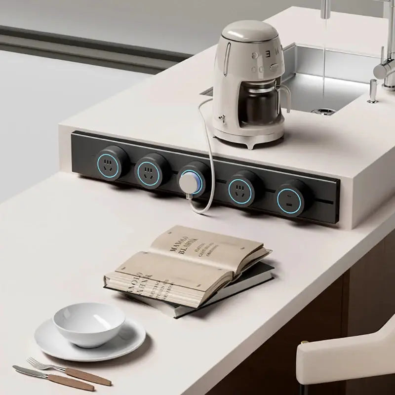 Embedded track socket power rail with five blue-ring outlets on a white kitchen island, coffee maker plugged in