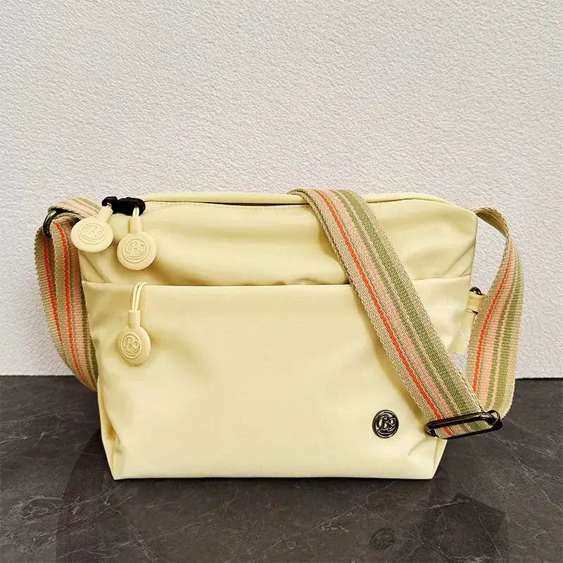 Ultra-light nylon crossbody bag in pale yellow with striped adjustable wide strap and zipper pocket Simples Market