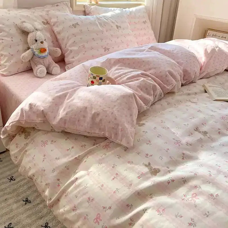 Pink floral bedding set with matching duvet cover, flat sheet and pillowcases on a bed.