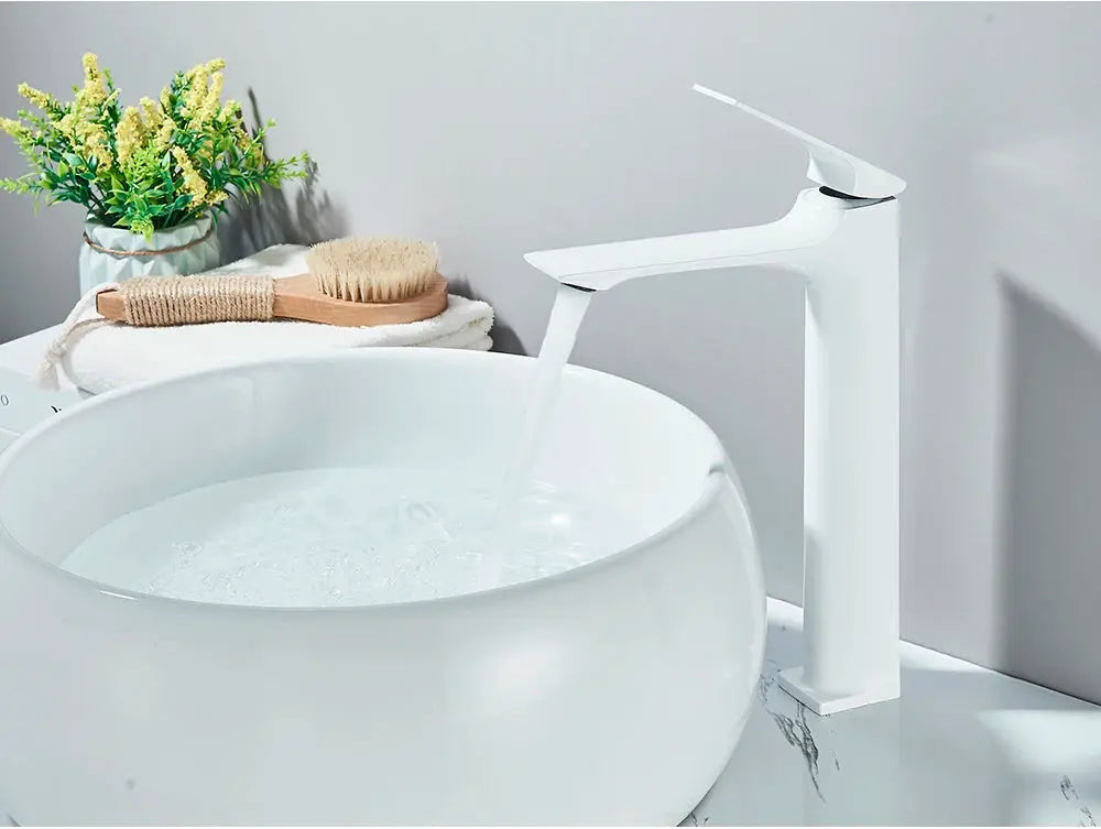 Deck-mounted bathroom faucet with single lever in white finish, water flows into a round white basin.