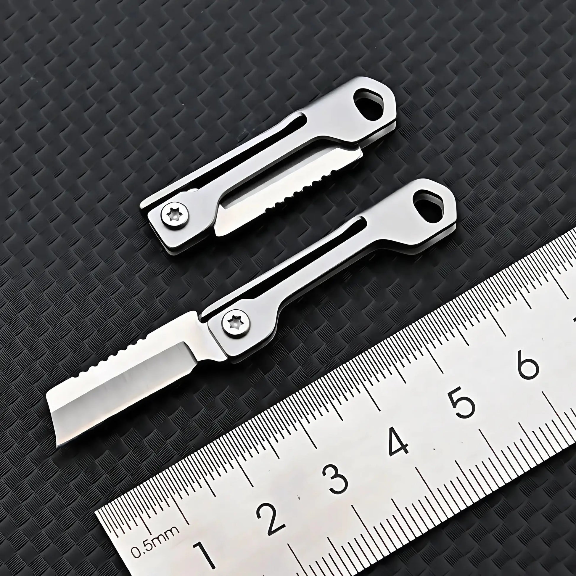 Stainless steel mini folding knife pair with keyhole ends on a ruler backdrop