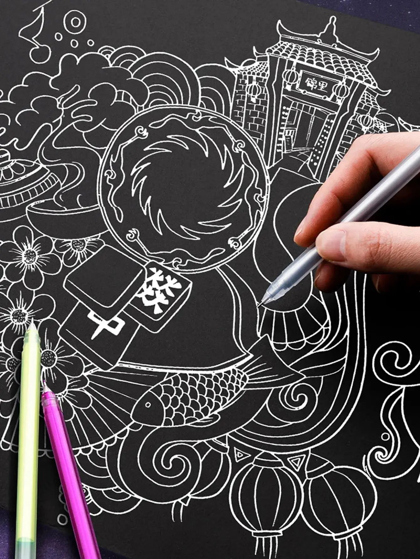 12-color gel pen set with 0.5mm fine tips for black cardstock drawing; hand holds a silver pen over white line-art illustration