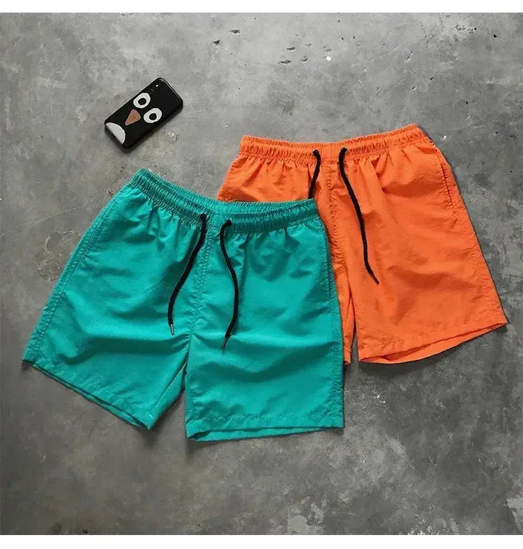 Men's swim shorts from Simples Market in teal and orange with black drawstrings, two pairs.