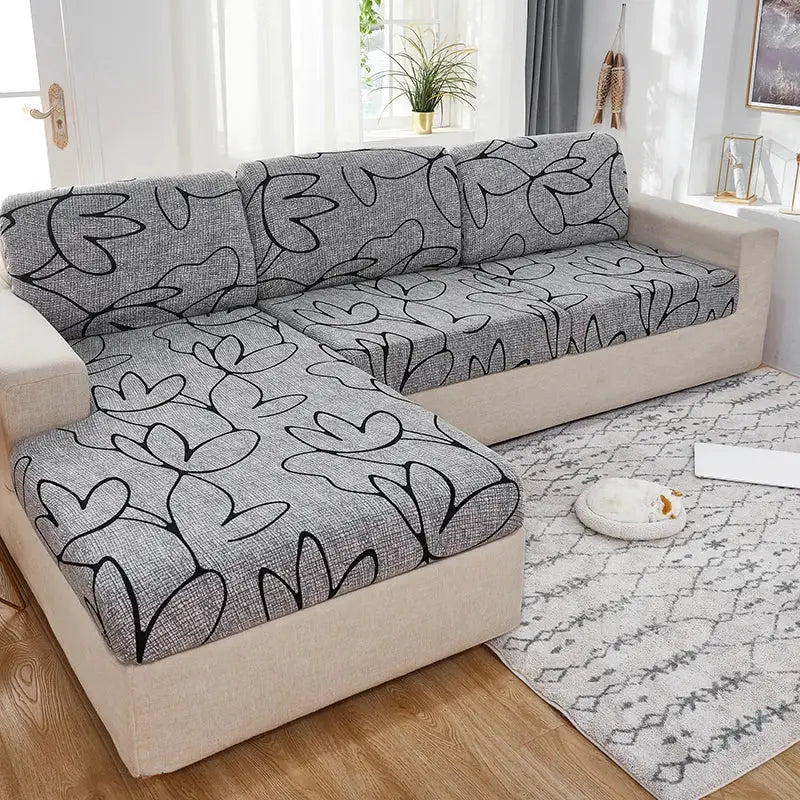 Gray elastic sofa slipcover with black abstract leaf pattern on sectional sofa cushions and ottoman