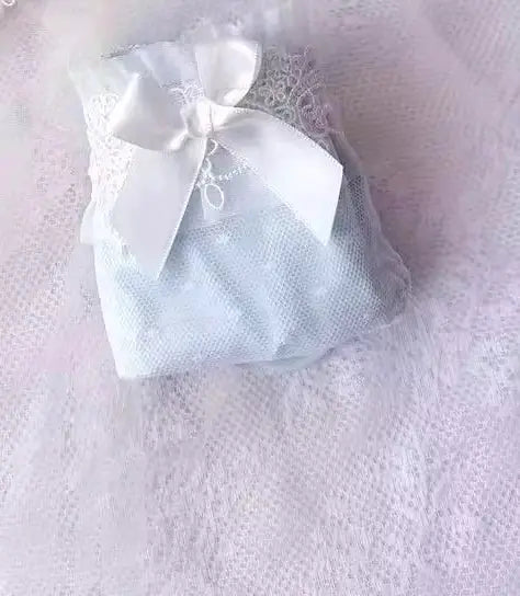 Lingerie bra set in a white mesh bag with satin bow on pink background