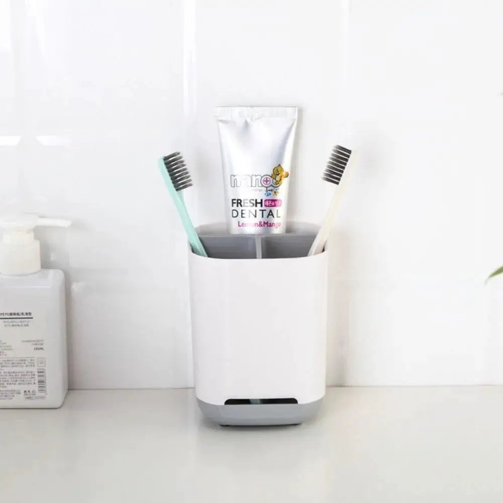 White bathroom toothbrush holder with two compartments on a countertop