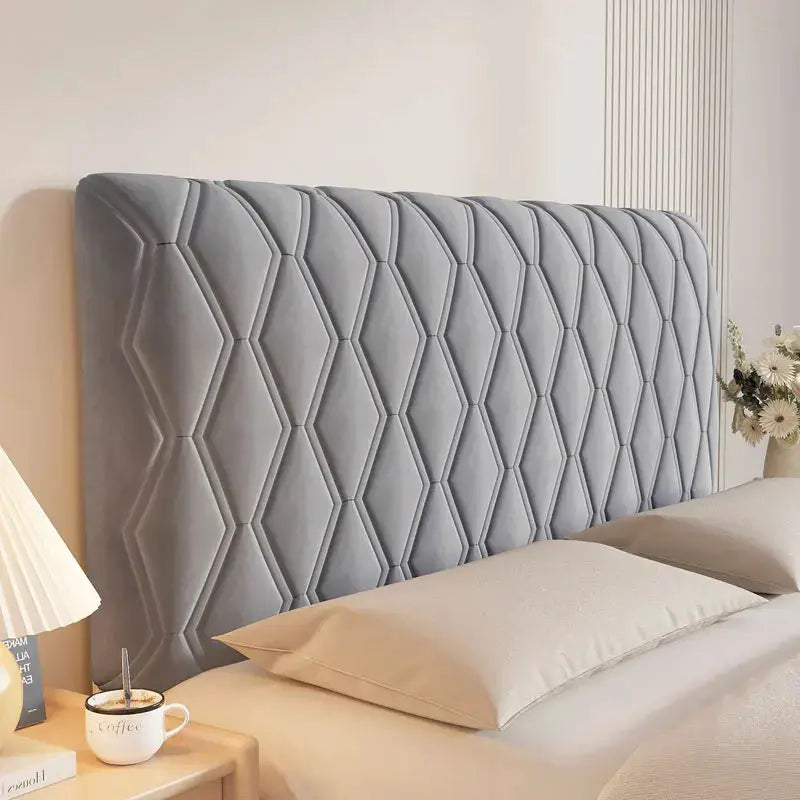 Velvet headboard cover with diamond-stitched pattern in solid gray on a bed with two beige pillows.