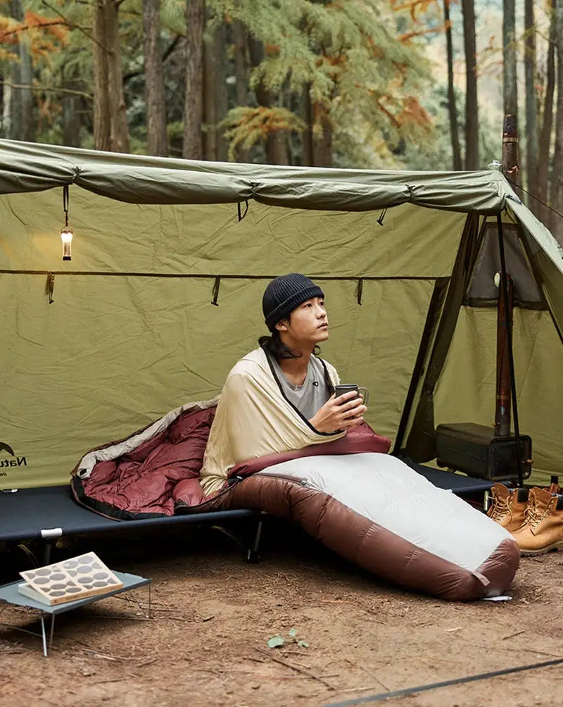 Naturehike ultralight mummy sleeping bag liner worn as a wearable camping quilt; brown and white inside a tent