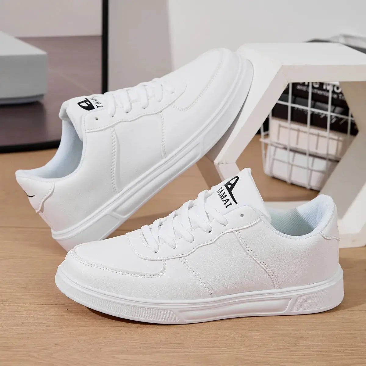 Pair of white leather men's sneakers with laces, breathable casual walking shoes.