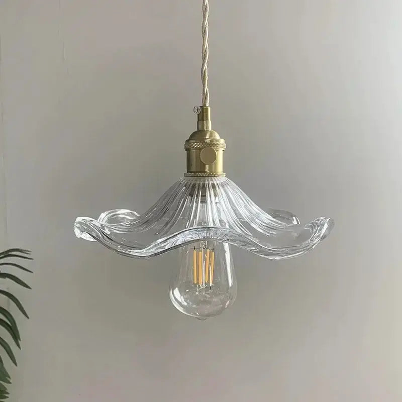 Pendant light with clear wavy glass shade, brass hardware and fabric cord, LED filament bulb included.