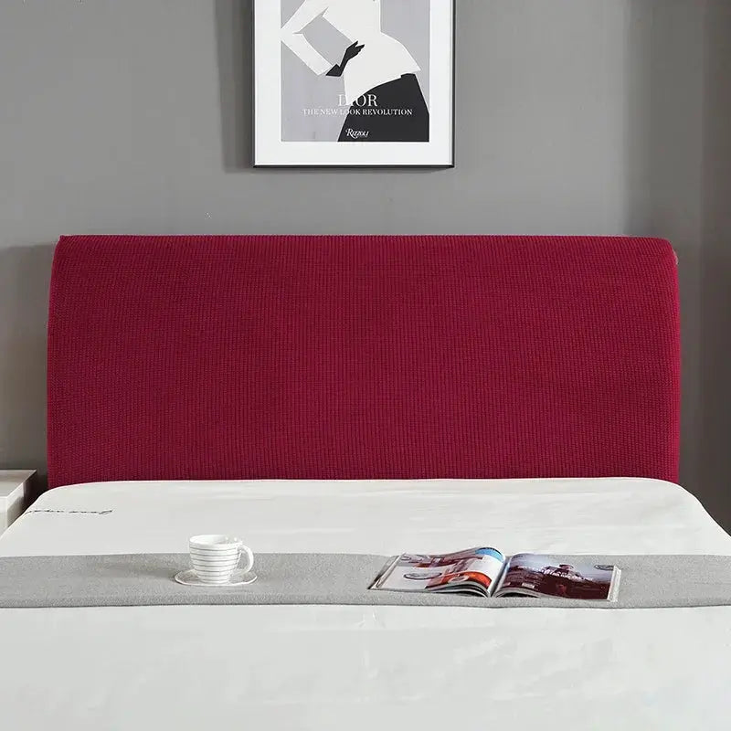 Bed headboard cover on a red upholstered headboard with white bedding and gray runner
