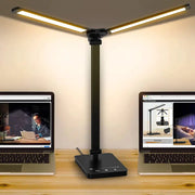 Double Head LED Desk Lamp with dual swing-arms, black finish, placed between two laptops