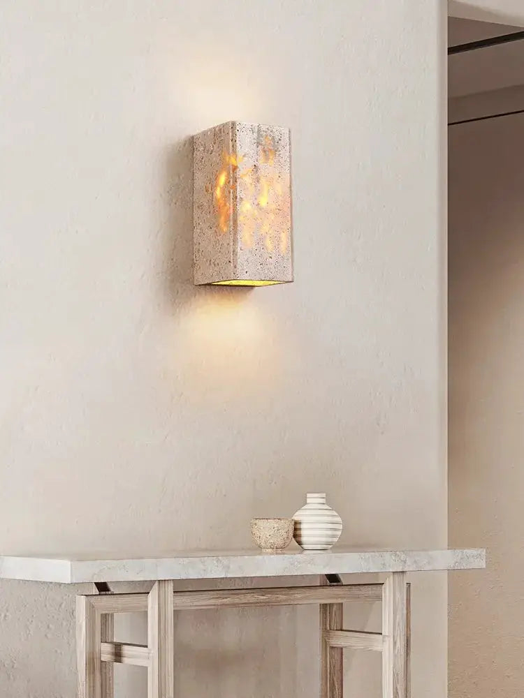 Marble wall lamp in yellow travertine with warm LED light.