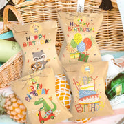 Kraft paper gift bags with colorful birthday designs featuring a rainbow dino, balloons and cake