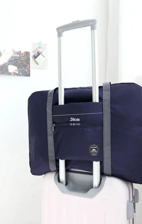 Large-capacity navy travel bag with gray straps, attached to a rolling suitcase; front zip pocket 20 cm.