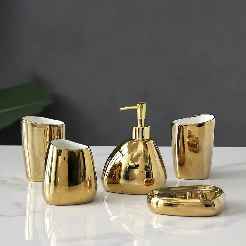 Gold bathroom accessory set with soap dispenser, mouthwash cup, toothbrush holder, and soap dish.