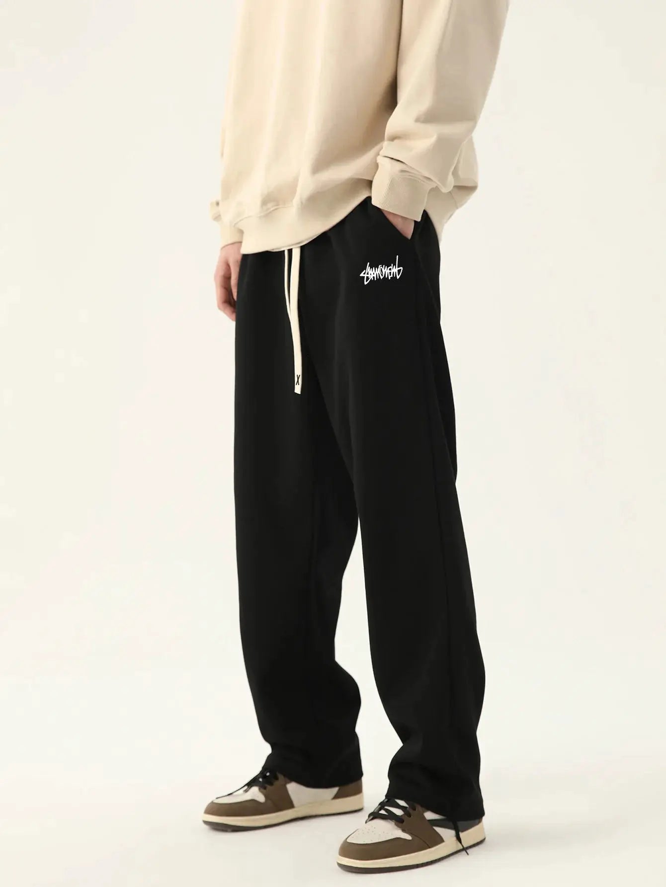 Men's black baggy joggers with white logo and drawstring waist.