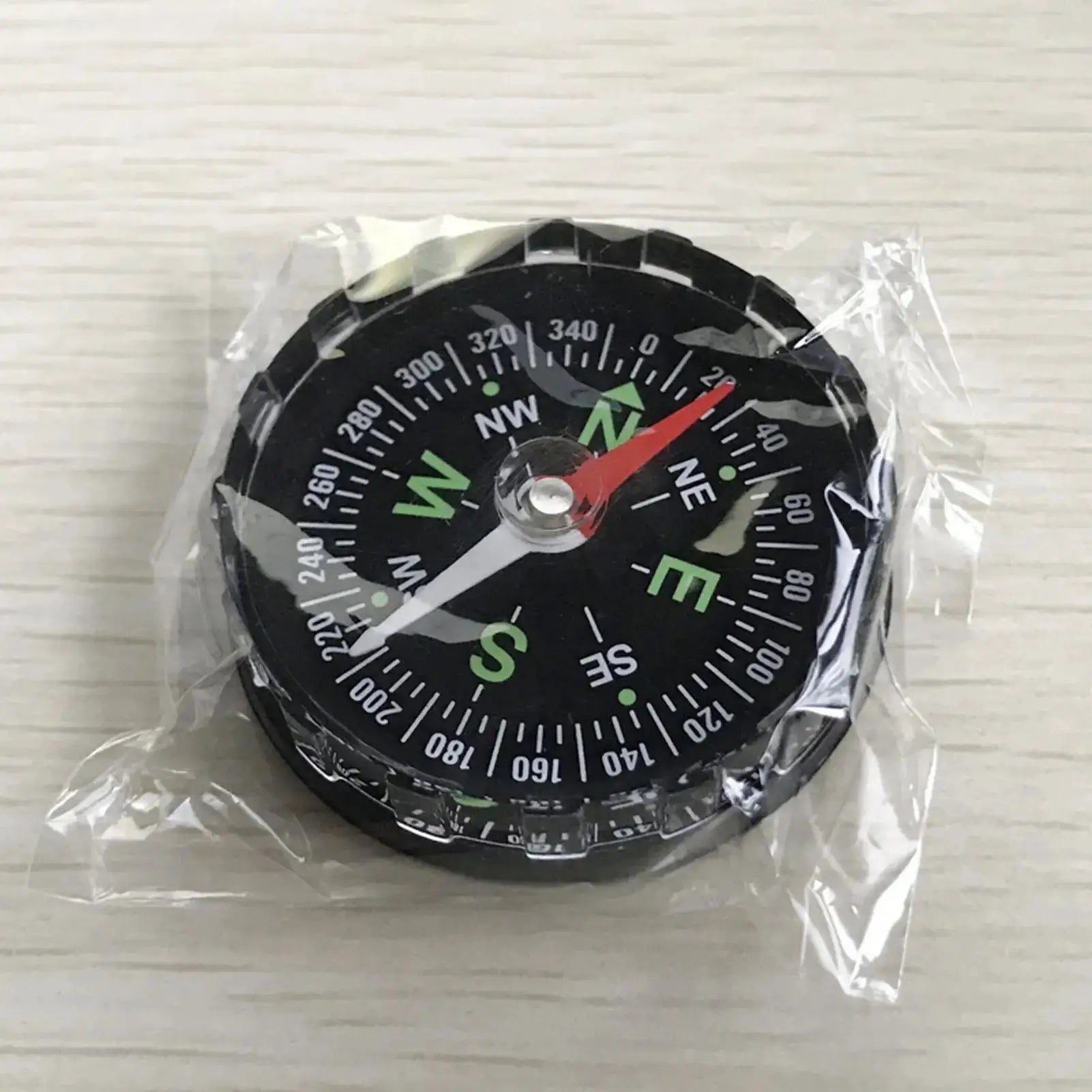 Waterproof hiking compass for outdoor navigation; black dial with red needle and green cardinal marks.