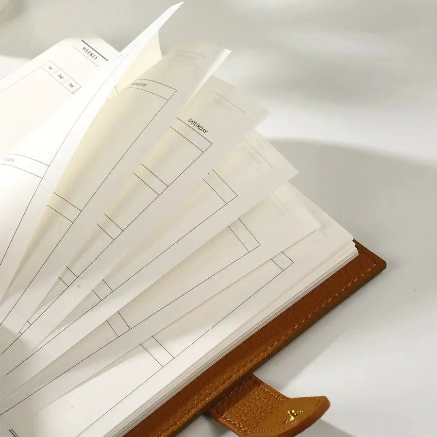 A6 Weekly Planner Notebook by Simples Market with compact brown leather cover and fanned weekly pages