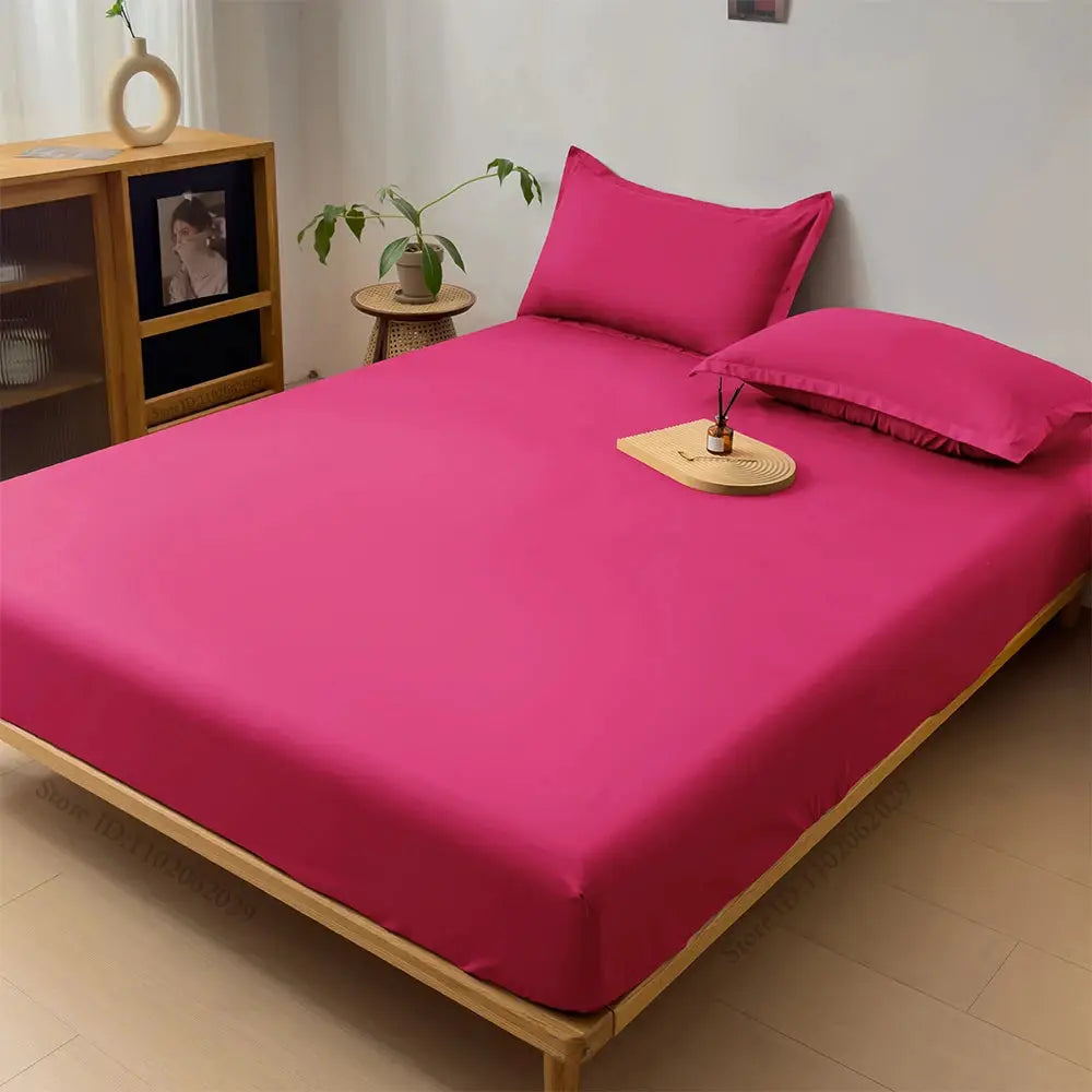 Fitted pink waterproof mattress cover by Simples Market on a wooden bed with pillows