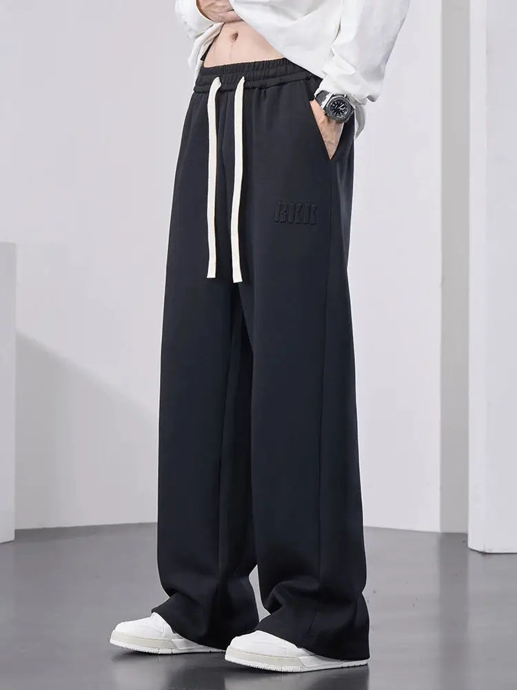 Men's black cotton track pants with white drawstring, elastic waist, wide-leg baggy long trousers.