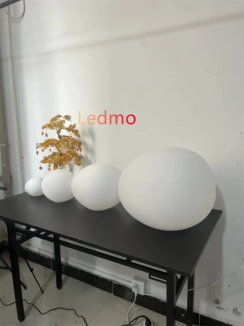 Ledmo white glass ball pendant lighting display with four round spheres on a black table