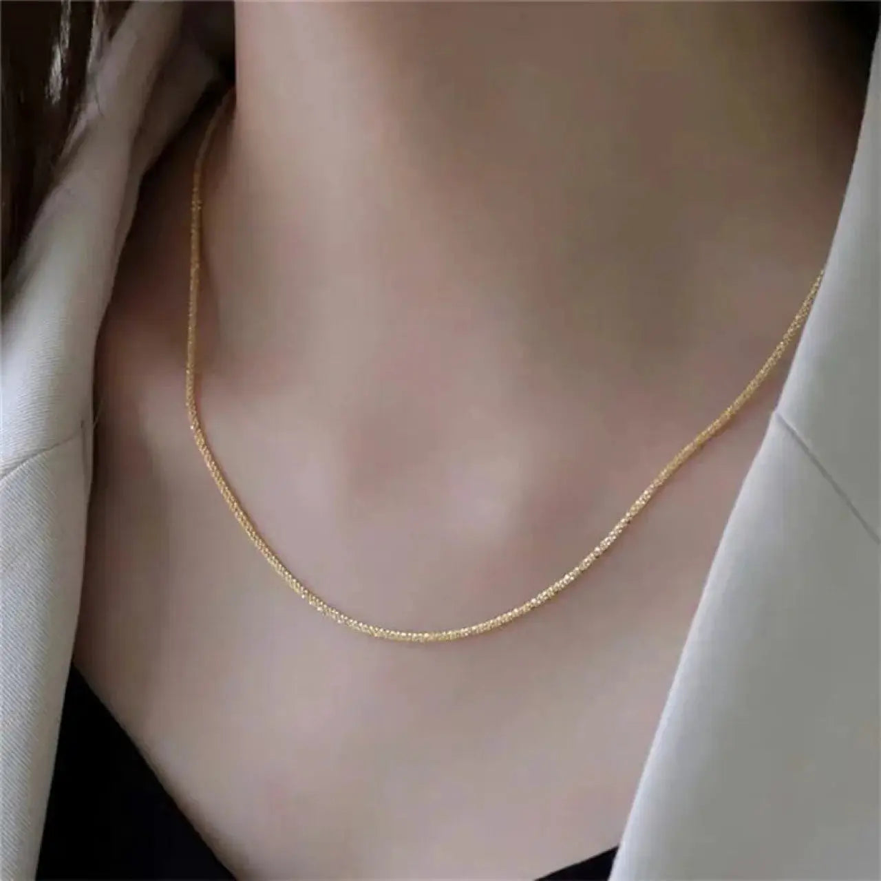 Gold-tone stainless steel chain necklace worn on a woman's neck.