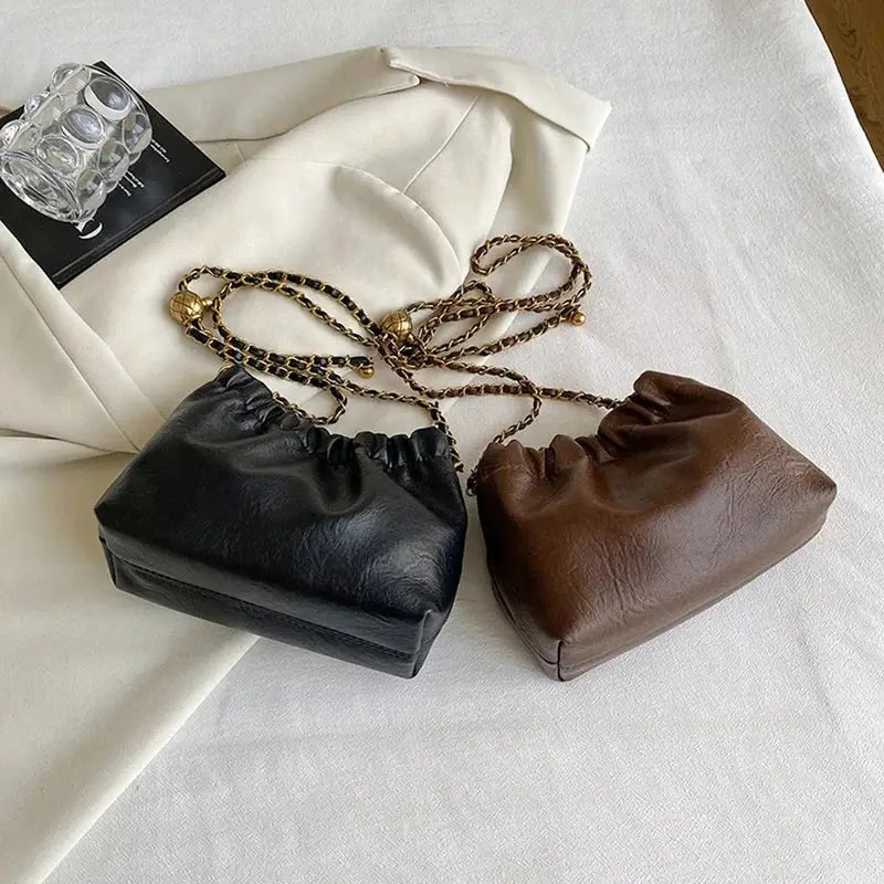 Two women's chain shoulder bags by Simples Market in black and brown faux leather with gold-tone chains.